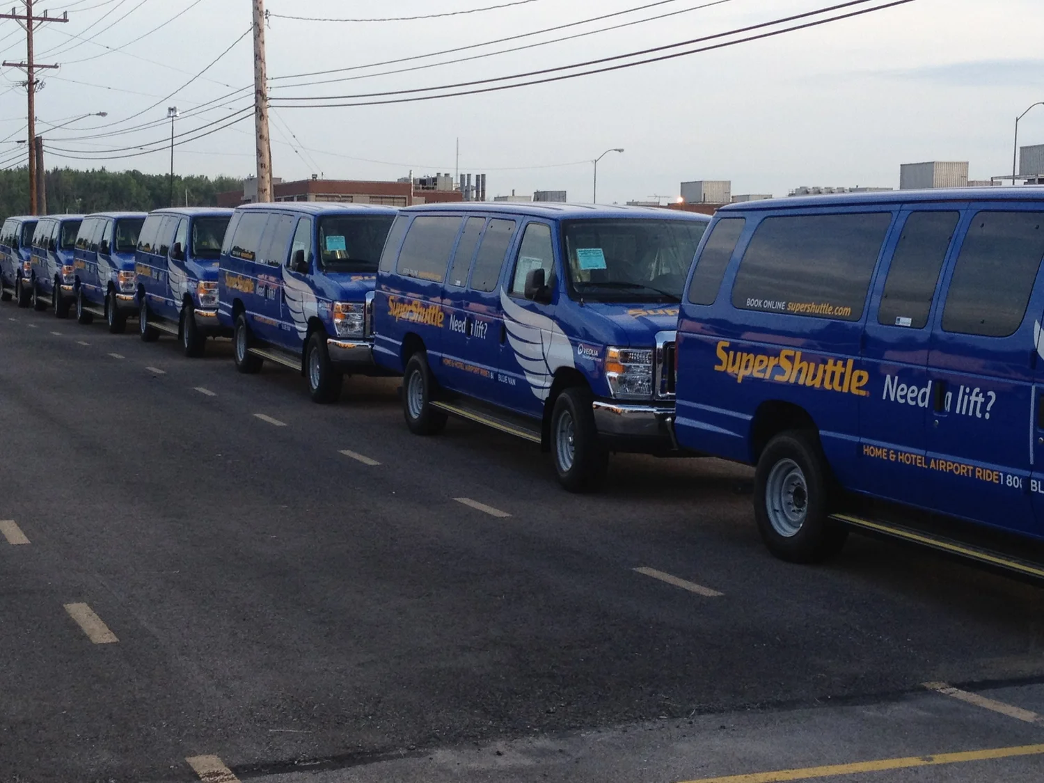 A long lineup of blue SuperShuttle vans with matching fleet graphics